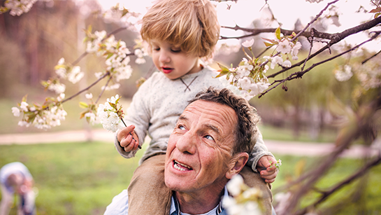 Mann mit Kleinkind auf den Schultern im Frühling