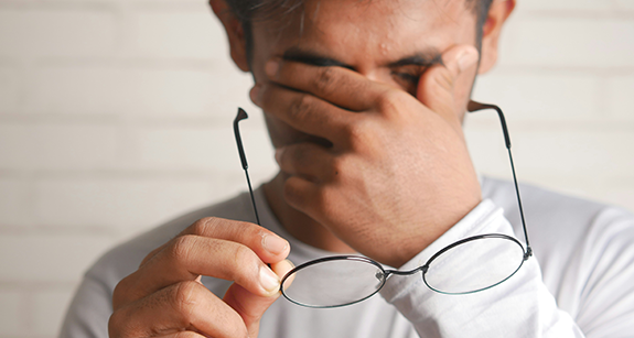 Ein Mann hält sich eine Brille vors Gesicht