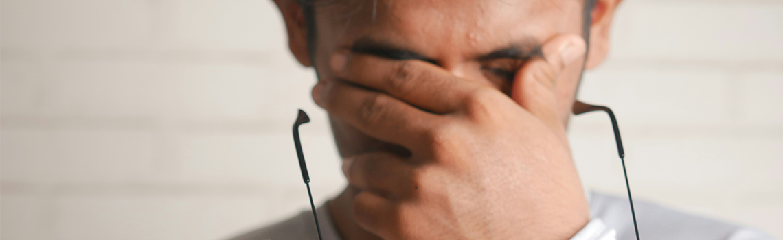 Ein Mann hält sich eine Brille vors Gesicht