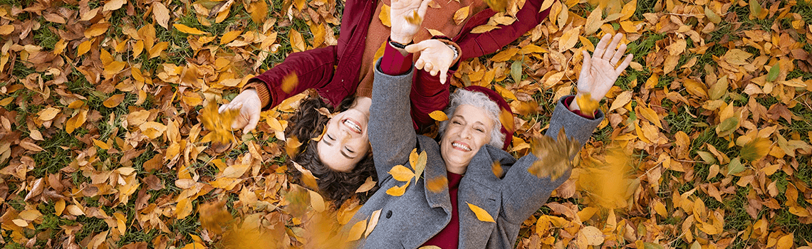 Großmutter und Enkelin liegen im Herbstlaub und genießen den Herbst
