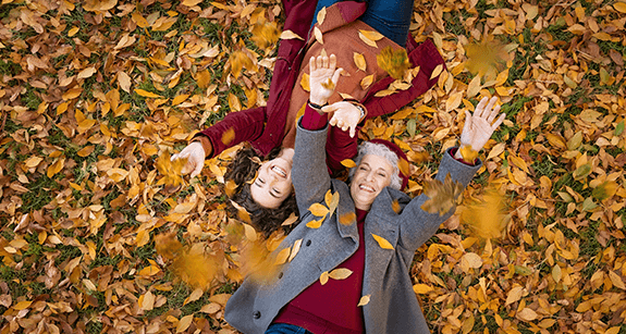 Großmutter und Enkelin liegen im Herbstlaub und genießen den Herbst