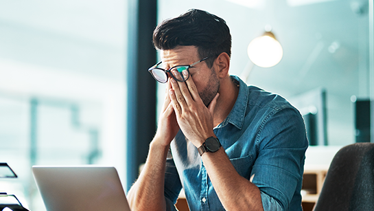 Kopfschmerzen, Stress und ein erschöpfter Geschäftsmann am Laptop im Büro