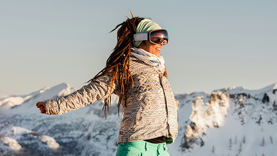 Frau in Winterkleidung mit Skibrille im Schnee